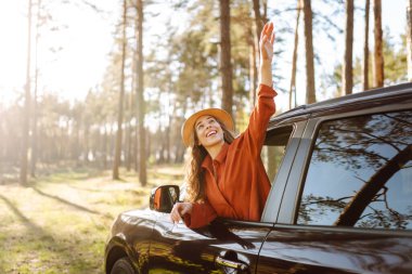 Kıvırcık saçlı genç bir kadının portresi arabanın camından gün batımını seyrediyor. Mutlu gezgin arabadan özgürlüğünü hissediyor. Özgürlük, macera konsepti.