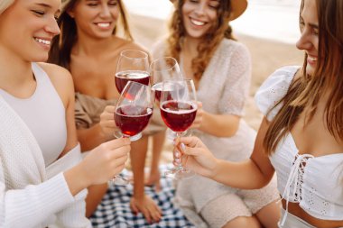 Mutlu kız arkadaşlar gün batımı kumsalında birlikte vakit geçiriyorlar. Ellerinde gözlüklerle dışarıda eğlenen dört güzel kadın. Arkadaşlık kavramı, eğlence. Yaşam biçimi.