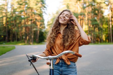 Genç bir kadın güneşli ormanda bisiklet sürmekten hoşlanıyor. Güzel bir turist gün batımında eğleniyor. Dinlenmek, yürümek. Etkin yaşam biçimi.