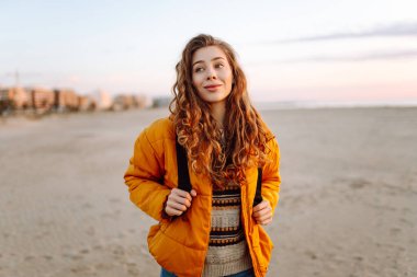 Genç bayan gezgin gün doğumunda kumlu sahilde yürüyor. Güzel bir kadın havanın tadını çıkarıyor ve dışarıda özgürlüğünü hissediyor. Yürümek, özgürlük kavramı.