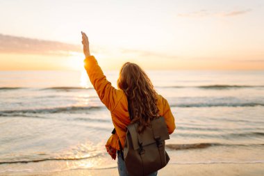 Genç bayan gezgin gün doğumunda kumlu sahilde yürüyor. Güzel bir kadın havanın tadını çıkarıyor ve dışarıda özgürlüğünü hissediyor. Yürümek, özgürlük kavramı.