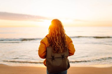 Genç bayan gezgin gün doğumunda kumlu sahilde yürüyor. Güzel bir kadın havanın tadını çıkarıyor ve dışarıda özgürlüğünü hissediyor. Yürümek, özgürlük kavramı.