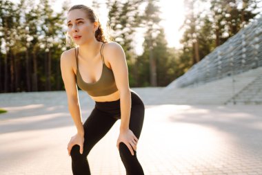 Spor yapan kadın gün batımında egzersiz yapıyor. Spor giyimli güzel bir kadın antrenmandan zevk alıyor ve dışarıda kendini güçlü hissediyor. Spor ve spor konsepti. Etkin yaşam biçimi.