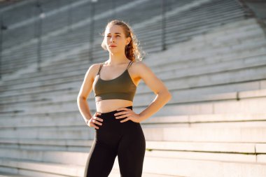 Spor yapan kadın gün batımında egzersiz yapıyor. Spor giyimli güzel bir kadın antrenmandan zevk alıyor ve dışarıda kendini güçlü hissediyor. Spor ve spor konsepti. Etkin yaşam biçimi.