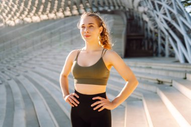 Spor yapan kadın gün batımında egzersiz yapıyor. Spor giyimli güzel bir kadın antrenmandan zevk alıyor ve dışarıda kendini güçlü hissediyor. Spor ve spor konsepti. Etkin yaşam biçimi.