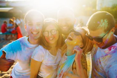 Mutlu arkadaşlar gün batımı kumsalında eğleniyorlar. Bir grup arkadaş birlikte vakit geçirip dışarıda festivali kutluyorlar. Holly kutlamaları. Arkadaşlık, eğlence konsepti..