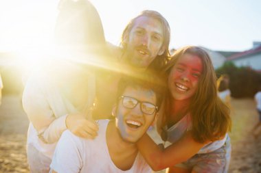 Mutlu arkadaşlar gün batımı kumsalında eğleniyorlar. Bir grup arkadaş birlikte vakit geçirip dışarıda festivali kutluyorlar. Holly kutlamaları. Arkadaşlık, eğlence konsepti..