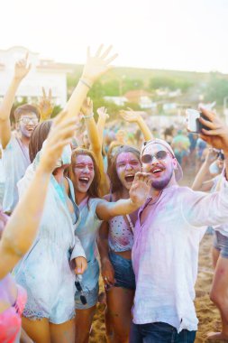 Mutlu arkadaşlar gün batımı kumsalında eğleniyorlar. Bir grup arkadaş birlikte vakit geçirip dışarıda festivali kutluyorlar. Holly kutlamaları. Arkadaşlık, eğlence konsepti..