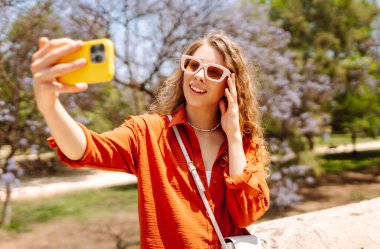 Selfie zamanı. Güneşli bir günde fotoğraf çeken ya da blog yazan güzel bir kadın. İyi tatiller. Bloglama, tatil kavramı.