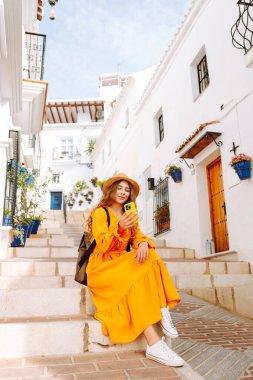 Şapkalı ve sırt çantalı güzel bir turist. Mesajlaşmalı ya da dışarıda elinde telefonla blog yazıyor. Telefonu olan, seyahatin ya da tatilin tadını çıkaran, sokaklarda yürüyen genç bir kadın. Etkin yaşam biçimi.