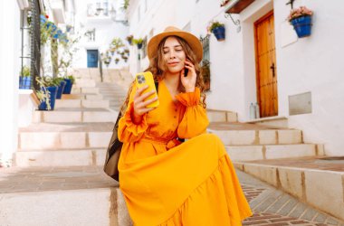 Şapkalı ve sırt çantalı güzel bir turist. Mesajlaşmalı ya da dışarıda elinde telefonla blog yazıyor. Telefonu olan, seyahatin ya da tatilin tadını çıkaran, sokaklarda yürüyen genç bir kadın. Etkin yaşam biçimi.