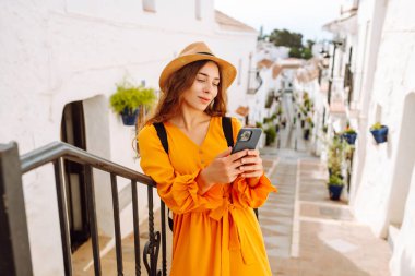 Şapkalı ve sırt çantalı güzel bir turist. Mesajlaşmalı ya da dışarıda elinde telefonla blog yazıyor. Telefonu olan, seyahatin ya da tatilin tadını çıkaran, sokaklarda yürüyen genç bir kadın. Etkin yaşam biçimi.