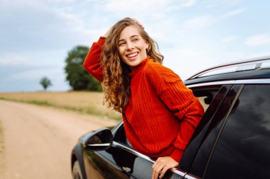 Mutlu kadın gezgin arabanın camından sarkan özgürlüğü hissediyor. Araba yolculuğundan hoşlanan genç bir kadın. Boş zaman kavramı, özgürlük. Seyahat tutkusu.