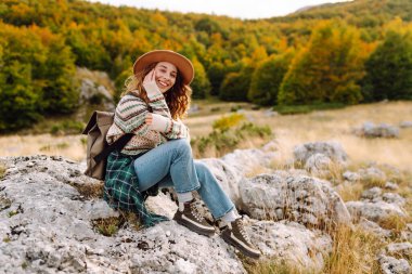 Şapkalı kadın gezgin kendini özgür hissediyor, dağlarda güneşli havanın tadını çıkarıyor. Seyahat tutkusu. Seyahat, tatil konsepti. Etkin yaşam biçimi.