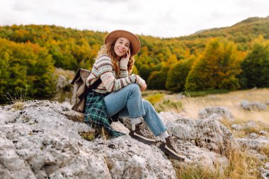 Şapkalı kadın gezgin kendini özgür hissediyor, dağlarda güneşli havanın tadını çıkarıyor. Seyahat tutkusu. Seyahat, tatil konsepti. Etkin yaşam biçimi.