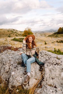 Şapkalı kadın gezgin kendini özgür hissediyor, dağlarda güneşli havanın tadını çıkarıyor. Seyahat tutkusu. Seyahat, tatil konsepti. Etkin yaşam biçimi.