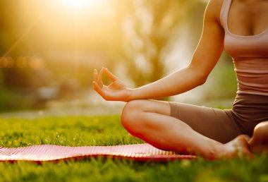 Sunny Park 'ta yoga minderi üzerinde egzersiz yapan genç bir kadın. Spor kıyafetli kadın dışarıda yoga yapıyor. Spor konsepti. Etkin yaşam biçimi.