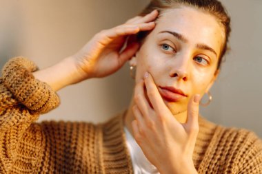 Yüzüne dokunan ve rahat bir odada aynaya bakan genç bir kadının portresi. Güzel bir kadın yüzündeki döküntüleri inceler, güzelliğinden zevk alır. Doğallık kavramı.