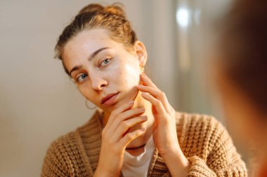 Yüzüne dokunan ve rahat bir odada aynaya bakan genç bir kadının portresi. Güzel bir kadın yüzündeki döküntüleri inceler, güzelliğinden zevk alır. Doğallık kavramı.