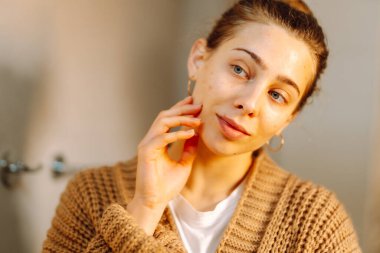 Yüzüne dokunan ve rahat bir odada aynaya bakan genç bir kadının portresi. Güzel bir kadın yüzündeki döküntüleri inceler, güzelliğinden zevk alır. Doğallık kavramı.