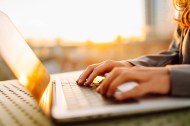 Bilgisayarda daktilo eden ellerin yakın çekimi. Gün batımında dizüstü bilgisayarda çalışan genç kadın eller. Serbest, teknoloji konsepti.