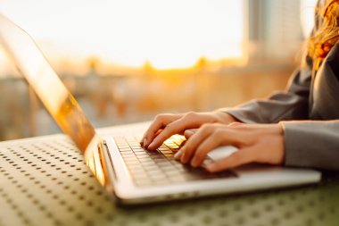 Bilgisayarda daktilo eden ellerin yakın çekimi. Gün batımında dizüstü bilgisayarda çalışan genç kadın eller. Serbest, teknoloji konsepti.
