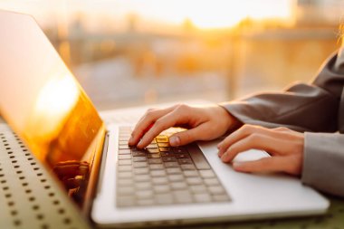 Bilgisayarda daktilo eden ellerin yakın çekimi. Gün batımında dizüstü bilgisayarda çalışan genç kadın eller. Serbest, teknoloji konsepti.