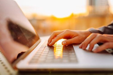 Bilgisayarda daktilo eden ellerin yakın çekimi. Gün batımında dizüstü bilgisayarda çalışan genç kadın eller. Serbest, teknoloji konsepti.