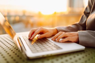 Bilgisayarda daktilo eden ellerin yakın çekimi. Gün batımında dizüstü bilgisayarda çalışan genç kadın eller. Serbest, teknoloji konsepti.
