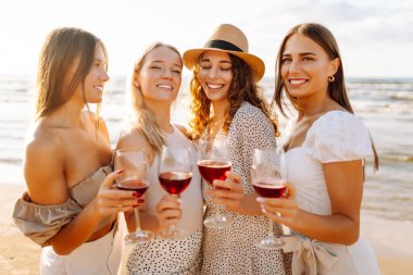 Genç kızlar eğleniyor, sahilde bir bardak şarapla yürüyorlar. Güzel dört kadın birlikte vakit geçiriyorlar, denizde günbatımının tadını çıkarıyorlar ve dinleniyorlar. Arkadaşlık kavramı, eğlence..