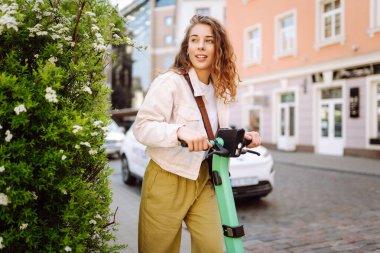 Elektrikli scooter kullanan güzel bir turist güneşli caddelerde geziyor. Genç bir kadın seyahat etmeyi, hafta sonlarını ve dışarıda yürümeyi seviyor. Yaşam biçimi.