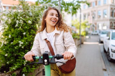 Elektrikli scooter kullanan güzel bir turist güneşli caddelerde geziyor. Genç bir kadın seyahat etmeyi, hafta sonlarını ve dışarıda yürümeyi seviyor. Yaşam biçimi.