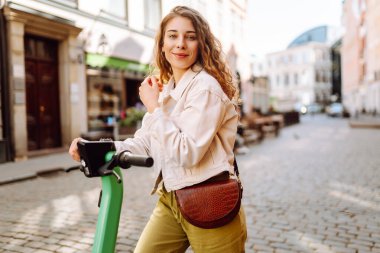Elektrikli scooter kullanan güzel bir turist güneşli caddelerde geziyor. Genç bir kadın seyahat etmeyi, hafta sonlarını ve dışarıda yürümeyi seviyor. Yaşam biçimi.