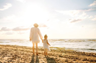 Güzel bir kadın ve çocuğu gün batımı kumsalında yürüyor. Genç bir anne ve kızı gün batımının tadını çıkarıp birlikte vakit geçiriyorlar. Hafta sonu, tatil kavramı.