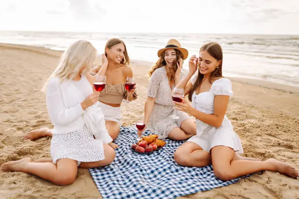 Açık havada şarap kadehleriyle pikniğe giden dört bayan arkadaş. Genç kadınlar gün batımında plajda birlikte dinlenmekten zevk alıyorlar. Arkadaşlık kavramı, rahatlama..