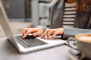 Dürbünlü güzel bir kadın dışarıda, masada çalışıyor. Kafede dizüstü bilgisayarı olan serbest çalışan bir kadın havanın tadını çıkarıyor. Teknoloji konsepti, uzaktan çalışma.