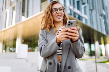 Şık giyinmiş, telefon kulübesinde oturan güzel bir kadın. Genç iş kadını dışarıda günbatımını seyrediyor. İş, günlük tutma kavramı.