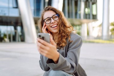 Şık giyinmiş, telefon kulübesinde oturan güzel bir kadın. Genç iş kadını dışarıda günbatımını seyrediyor. İş, günlük tutma kavramı.