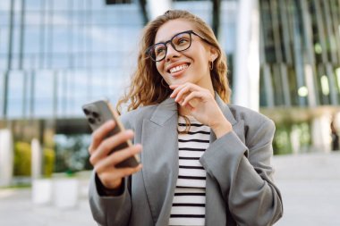 Şık giyinmiş, telefon kulübesinde oturan güzel bir kadın. Genç iş kadını dışarıda günbatımını seyrediyor. İş, günlük tutma kavramı.