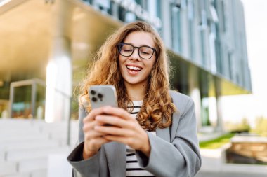 Şık giyinmiş, telefon kulübesinde oturan güzel bir kadın. Genç iş kadını dışarıda günbatımını seyrediyor. İş, günlük tutma kavramı.