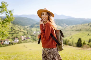 Mutlu kadın özgürlüğün yemyeşil bir alanda durduğunu hissediyor. Güzel bir kadın dağ manzarasından zevk alıyor ve doğada dinleniyor. Doğa ve keyif kavramı.