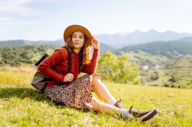 Mutlu kadın özgürlüğün yemyeşil bir alanda durduğunu hissediyor. Güzel bir kadın dağ manzarasından zevk alıyor ve doğada dinleniyor. Doğa ve keyif kavramı.