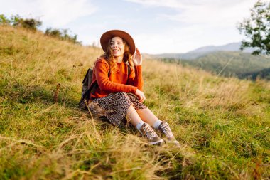 Mutlu kadın özgürlüğün yemyeşil bir alanda durduğunu hissediyor. Güzel bir kadın dağ manzarasından zevk alıyor ve doğada dinleniyor. Doğa ve keyif kavramı.