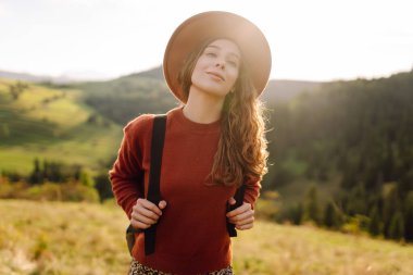 Mutlu kadın özgürlüğün yemyeşil bir alanda durduğunu hissediyor. Güzel bir kadın dağ manzarasından zevk alıyor ve doğada dinleniyor. Doğa ve keyif kavramı.
