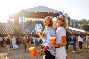 Bir plaj partisinde bira içip eğlenen mutlu bayan arkadaşlar. İki genç bayan arkadaş sahildeki bir müzik festivalinde tatilin tadını çıkarıyorlar. Arkadaşlık ve eğlence konsepti.