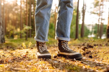 Güneşli ormanda yürüyüş botlarıyla bacaklarınızı kapatın. Kapalı ayakkabılarla ormanda yürüyüp doğanın tadını çıkaran bir kadın yürüyüşçü. Yürüyüş ve keyif konsepti.