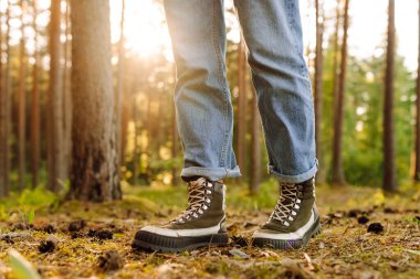 Güneşli ormanda yürüyüş botlarıyla bacaklarınızı kapatın. Kapalı ayakkabılarla ormanda yürüyüp doğanın tadını çıkaran bir kadın yürüyüşçü. Yürüyüş ve keyif konsepti.