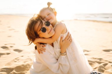 Güzel bir kadın kızıyla denizde eğleniyor. Mutlu anne ve çocuk gün batımında eğleniyor ve dışarıda birlikte vakit geçiriyorlar. Annelik ve aşk kavramı.