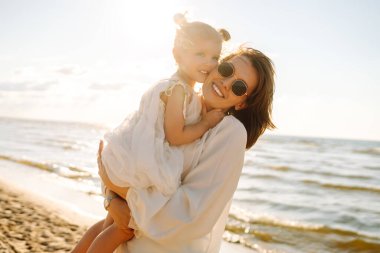 Güzel bir kadın kızıyla denizde eğleniyor. Mutlu anne ve çocuk gün batımında eğleniyor ve dışarıda birlikte vakit geçiriyorlar. Annelik ve aşk kavramı.