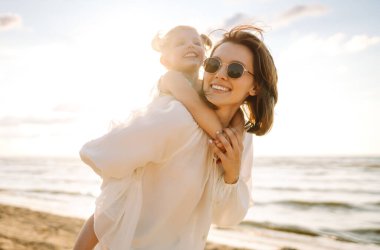 Güzel bir kadın kızıyla denizde eğleniyor. Mutlu anne ve çocuk gün batımında eğleniyor ve dışarıda birlikte vakit geçiriyorlar. Annelik ve aşk kavramı.